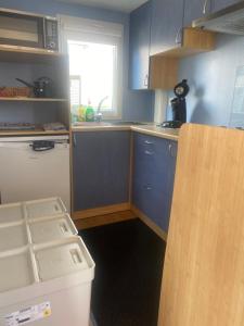 a small kitchen with blue cabinets and a window at Chalet Sonnenschein in Bredene