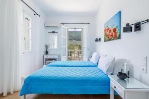 Un dormitorio blanco con una cama azul y una ventana en Stafylos Green, en Skopelos Town