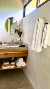 a bathroom with a sink and a mirror and towels at Sharma Costa Rica - Heliconia Casita in Uvita