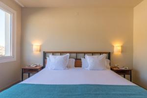 a bedroom with a bed with white pillows and a window at Hotel Hostalillo by Escampa Hotels in Tamariu