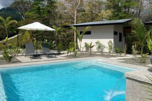 uma piscina com cadeiras e um guarda-sol ao lado de uma casa em Sharma Costa Rica - Heliconia Casita em Uvita