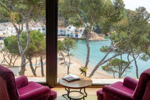 a room with two chairs and a table and a large window at Hotel Hostalillo by Escampa Hotels in Tamariu