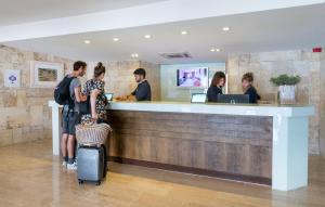 a group of people standing at a bar with luggage at Hotel Hostalillo by Escampa Hotels in Tamariu