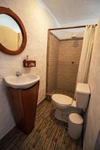 a bathroom with a sink and a toilet and a mirror at Hotel Casa Blanca in Puerto Baquerizo Moreno
