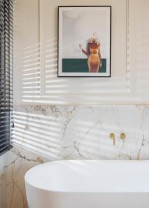 baño con bañera blanca y una foto en la pared en Damson - Machne Yehuda Hotel, en Jerusalén