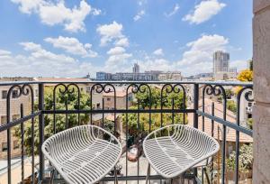 two chairs on a balcony with a view of a city at Damson - Machne Yehuda Hotel in Jerusalem