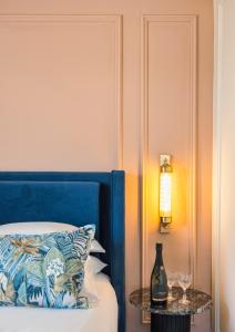 a bed with a blue headboard and a table with wine glasses at Damson - Machne Yehuda Hotel in Jerusalem