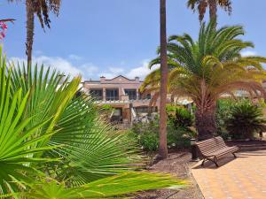 a park with a bench and palm trees and a building at Modern Townhouse Ocean Front in Adeje