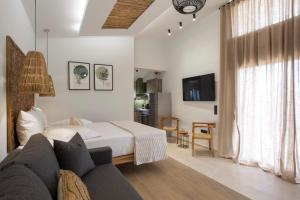 a bedroom with a bed and a couch and a tv at ELFAM CITY SUITES in Lefkada Town