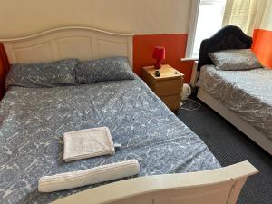 een slaapkamer met 2 bedden en een nachtkastje met een lamp bij Malvern Lodge Guest House- Close to Beach, Train Station & Southend Airport in Southend-on-Sea