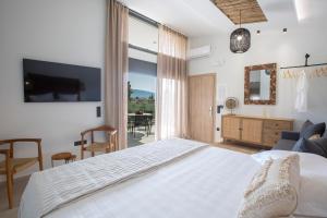 a bedroom with a white bed and a large window at ELFAM CITY SUITES in Lefkada