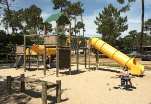 a playground with a yellow slide in the sand at A la brise du Ferret - Camping les Embruns in Lège-Cap-Ferret