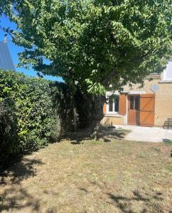 een boom in een tuin naast een huis bij Charmante maison à la campagne in Sainte-Fauste