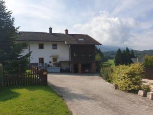 ein weißes Haus mit einem Zaun und einer Einfahrt in der Unterkunft Ferienwohnung Hagner in Teisendorf