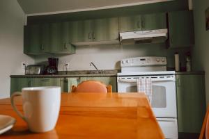 a kitchen with green cabinets and a table with a coffee cup at Auberge L'Orpailleur in Val-dʼOr