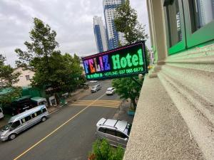 un panneau indiquant un hôtel avec des voitures garées dans une rue dans l'établissement Feliz Hotel Binh Duong, à Thu Dau Mot