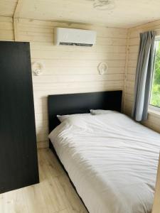 a bed in a small room with a black headboard at Tiny house aan het water op de appelhof in Wommels