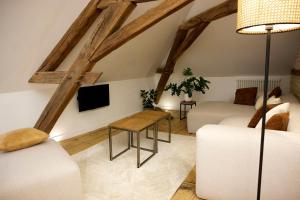 サヴィニー・レ・ボーヌにあるCouette&Livingの白い家具と木製の梁が備わるリビングルーム