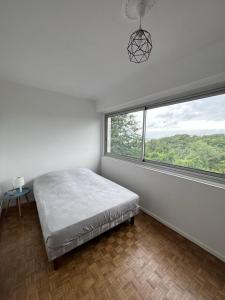 1 dormitorio con cama y ventana grande en Beau Duplex Cenon résidence calme, vue arborée, en Cenon