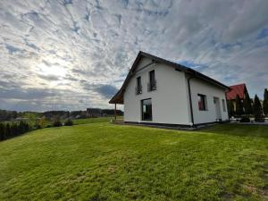 OsłoninDomek Osłonin的一座白色的小房子,位于大草地上