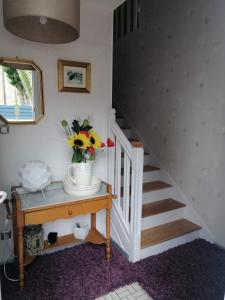 a staircase with a vase of flowers on a table at Ty Pempoul - logement 2 chambres - 100 m de la plage in Saint-Pol-de-Léon