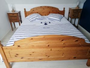 a large wooden bed with a wooden headboard in a bedroom at Ty Pempoul - logement 2 chambres - 100 m de la plage in Saint-Pol-de-Léon
