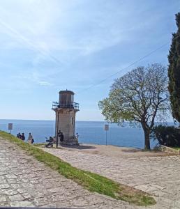 ein Leuchtturm an der Seite einer Straße neben dem Meer in der Unterkunft ELLE in Rovinj