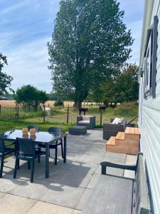 eine Terrasse mit einem Tisch, Stühlen und einem Feld in der Unterkunft Het Hoefje in Sint-Annaland