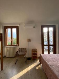 a bedroom with a bed and a chair and windows at La Casa di Nora in Turin