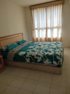a bedroom with a bed with a green comforter and a window at Homestay Pantai Puteri in Kampong Bukit Darat +6 photos