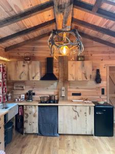 cocina con paredes de madera y techo con lámpara de araña. en Le chalet du Hélivy en Jalhay