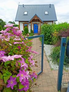 una puerta frente a una casa con flores púrpuras en Żuławska Osada, 