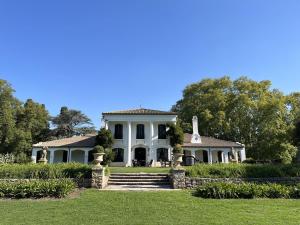 a white house with a porch and a lawn at Casa de campo en club privado Benquerencia in San Miguel del Monte