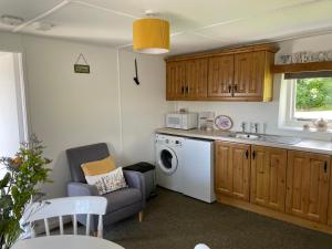 a kitchen with a washing machine and a chair at Anne’s Thatched Cottage in Kilcar