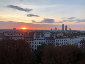 Blick auf eine Stadt mit Sonnenuntergang im Hintergrund in der Unterkunft Superbe Duplex rénové avec vue exceptionnelle sur Lyon in Lyon