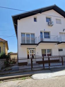 ein weißes Haus mit einem schwarzen Zaun in der Unterkunft Apartmani SKY 1 2 3 in Brčko