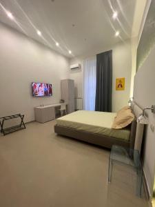 Un dormitorio con una cama y un televisor en una pared. en Dimora Chiaia 209, en Nápoles