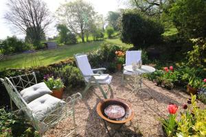 two chairs and a table in a garden with flowers at Gorgeous romantic cosy cottage retreat with views in Winster