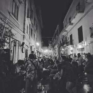 una multitud de personas sentadas en mesas en una calle por la noche en Sicily Home-affittacamere mediterraneo, en Marsala