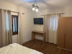 um quarto com uma cama, uma televisão e cortinas em Vila Alba em Korçë