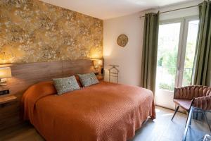 1 dormitorio con cama y ventana grande en Hôtel l'Amandière en Saint-Rémy-de-Provence