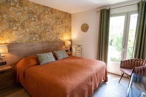 a bedroom with a bed and a large window at Hôtel l'Amandière in Saint-Rémy-de-Provence