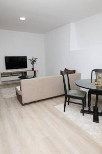 a living room with a couch and a table and a tv at Gramosli Apartment in Bitola