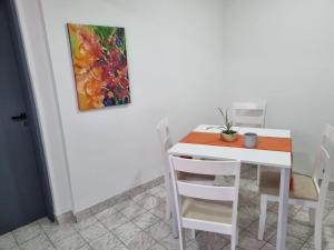 una mesa y sillas blancas con una pintura en la pared en Hermoso departamento con patio en Rio Gallegos en Río Gallegos