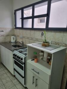 cocina con fogones y fregadero y 2 ventanas en Hermoso departamento con patio en Rio Gallegos en Río Gallegos