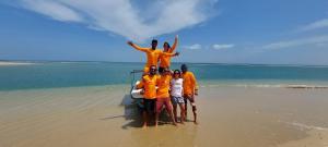 un grupo de personas con camisas naranjas de pie en la playa en BLUE WAVES kite surfing beach resort en Kalpitiya