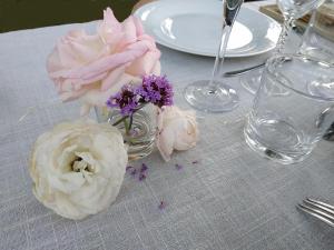 stół z dwoma pączkami i kwiatami w wazie w obiekcie La Villauvert - Cottage w mieście Saint-Martin-sur-Oust