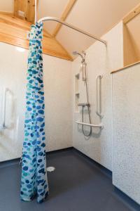 a bathroom with a shower with a blue curtain at Wigwam Holidays Forcett Grange in Richmond