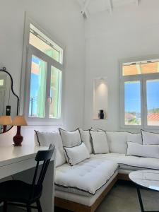 a white living room with a white couch and two windows at Syboro in Aloïziánika