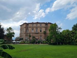 um grande edifício com um campo verde em frente em B and B da Magna Cichina em Collegno